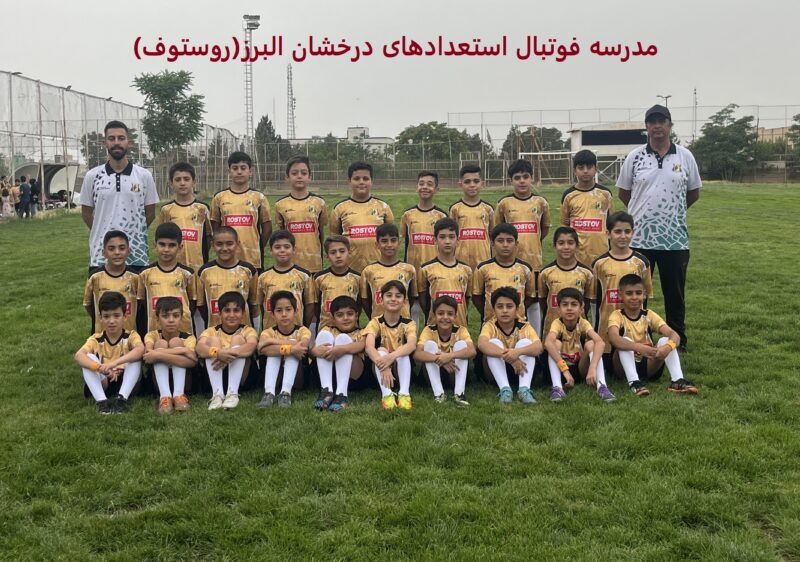 عکس گروهی از تیم فوتبال جوانان در کرج، با 16 بازیکن در لباس زرد و مشکی با لوگوی "Rosto"، ایستاده و نشسته روی زمین چمن، همراه دو مربی با لباس سفید، با متن "مدرسه فوتبال استعدادهای درخشان" در بالا، نمایش‌دهنده آموزش حرفه‌ای و روحیه تیمی