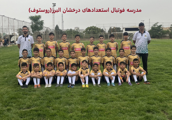عکس گروهی از تیم فوتبال نوجوانان در کرج، با 16 بازیکن در لباس زرد و مشکی با لوگوی "Rosto"، ایستاده و نشسته روی زمین چمن، همراه دو مربی با لباس سفید، با متن "مدرسه فوتبال استعدادهای درخشان" در بالا، نمایش‌دهنده آموزش حرفه‌ای و روحیه تیمی